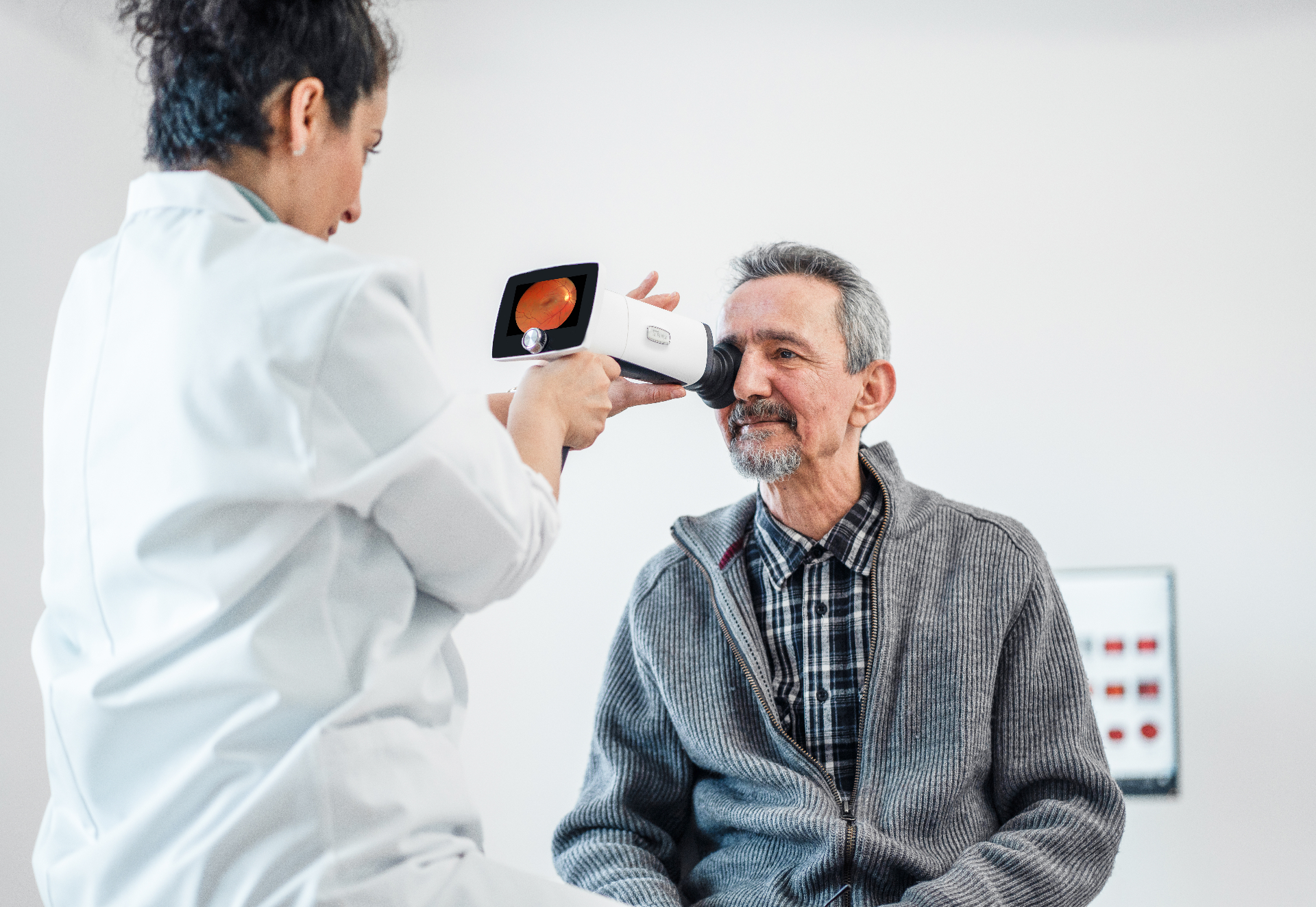 Clinician using a handheld fundus camera to capture a retinal image of an elderly patient